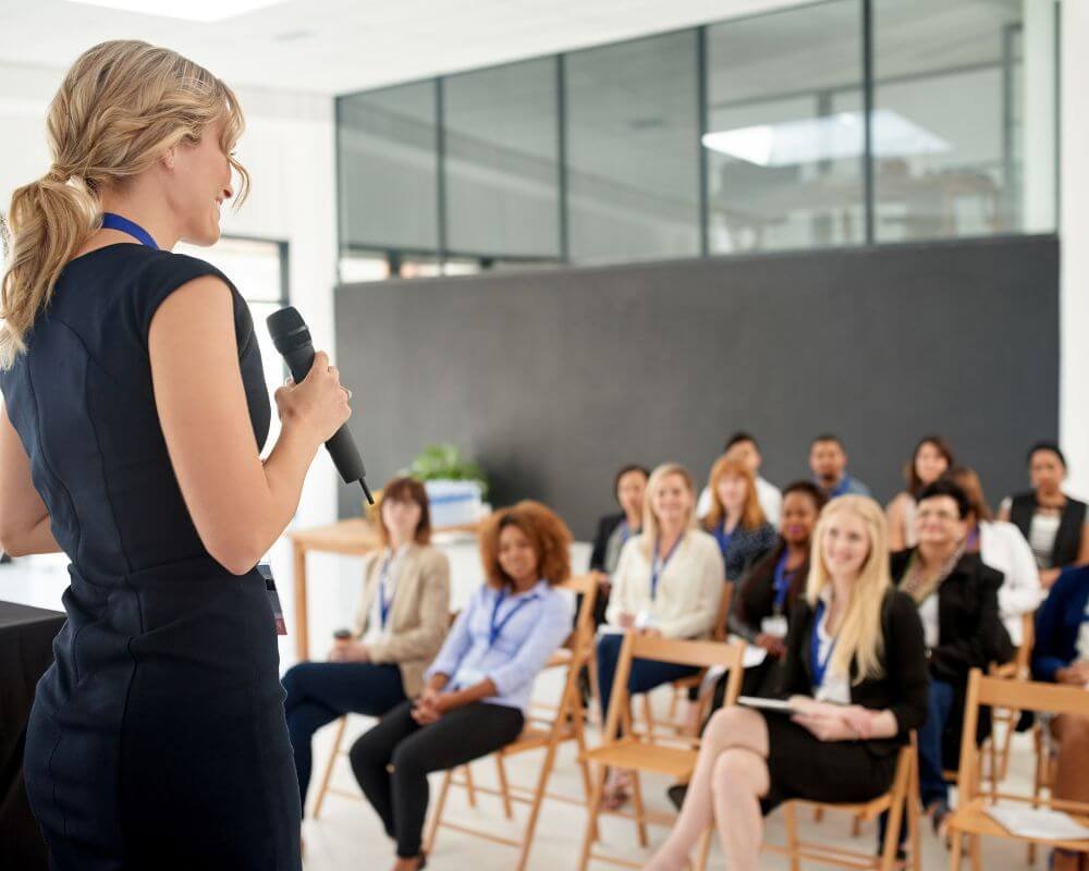 Een vrouw die een toespraak geeft aan een zaal vol bedrijfspersoneel